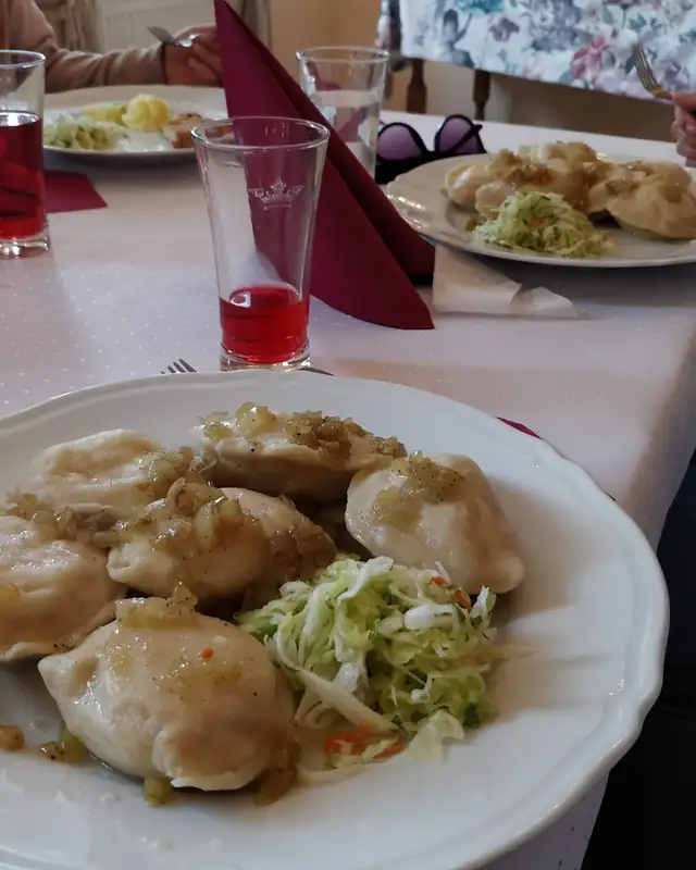 Talerz pierogów z surówką z kapusty na stole z białym obrusem