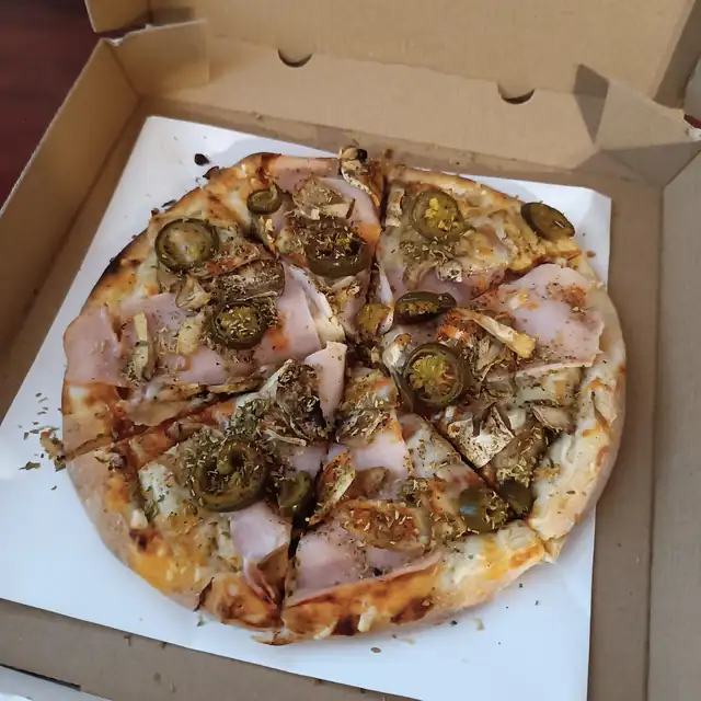 Pizza z szynką i jalapeño w otwartym kartonie na wynos