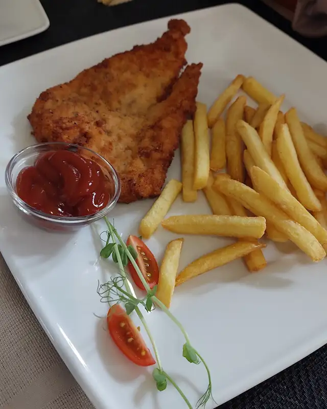 Panierowany kotlet z frytkami, pomidorem i keczupem